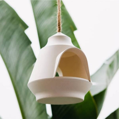 Annabel trends Bamboo Bird House Cream hanging, green leaves behind